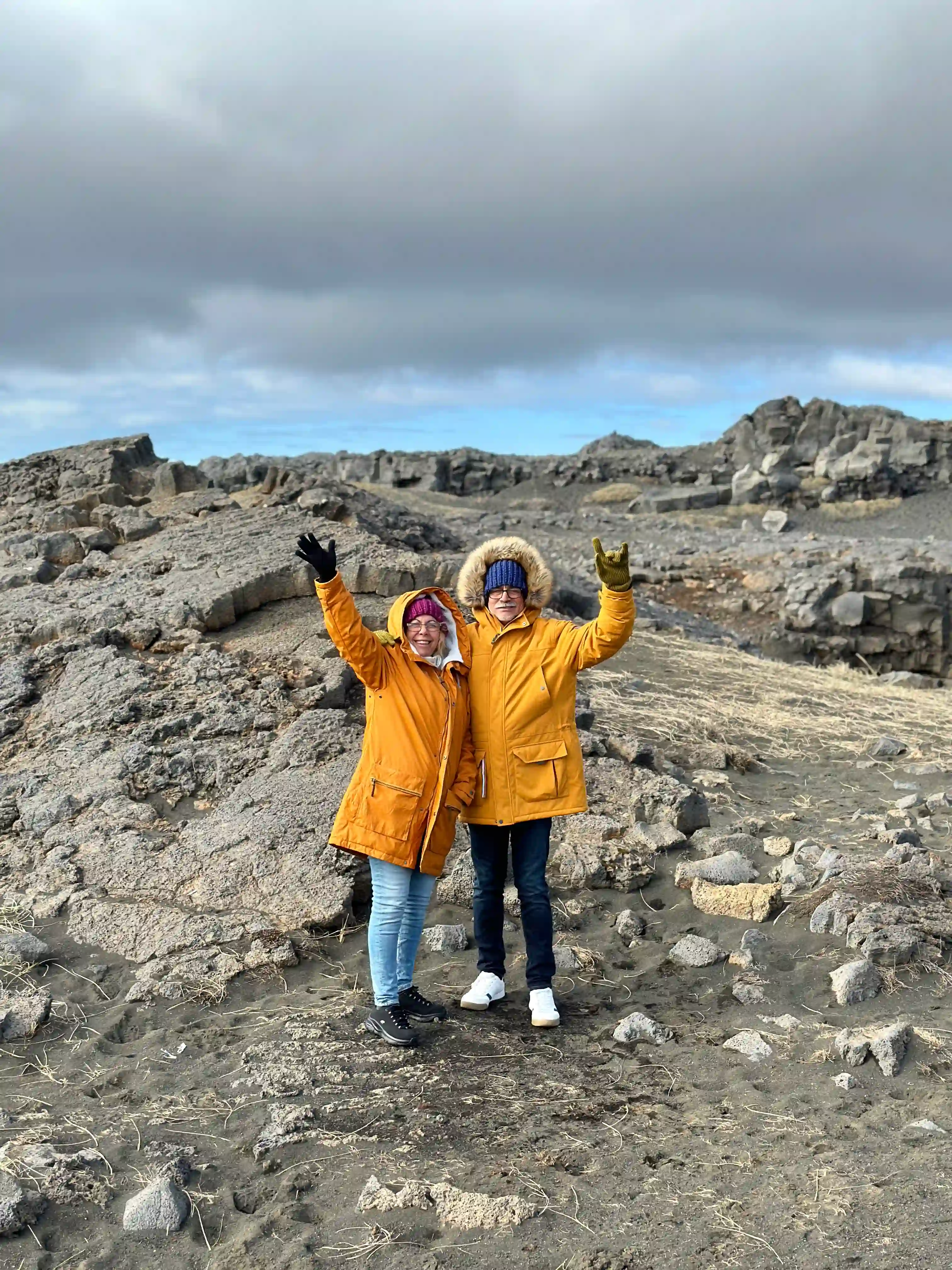 A couple standing over the black lava rocks near the bridge between continents in Reykjane