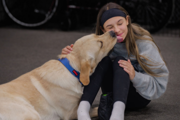 Gold Star child bonding with her fully trained service dog, receiving affection and emotional support as part of the healing process.