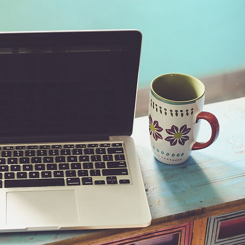 lap top abierta y una taza de café junto