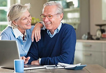 Elderly couple happily setting up insurance coverage on a computer