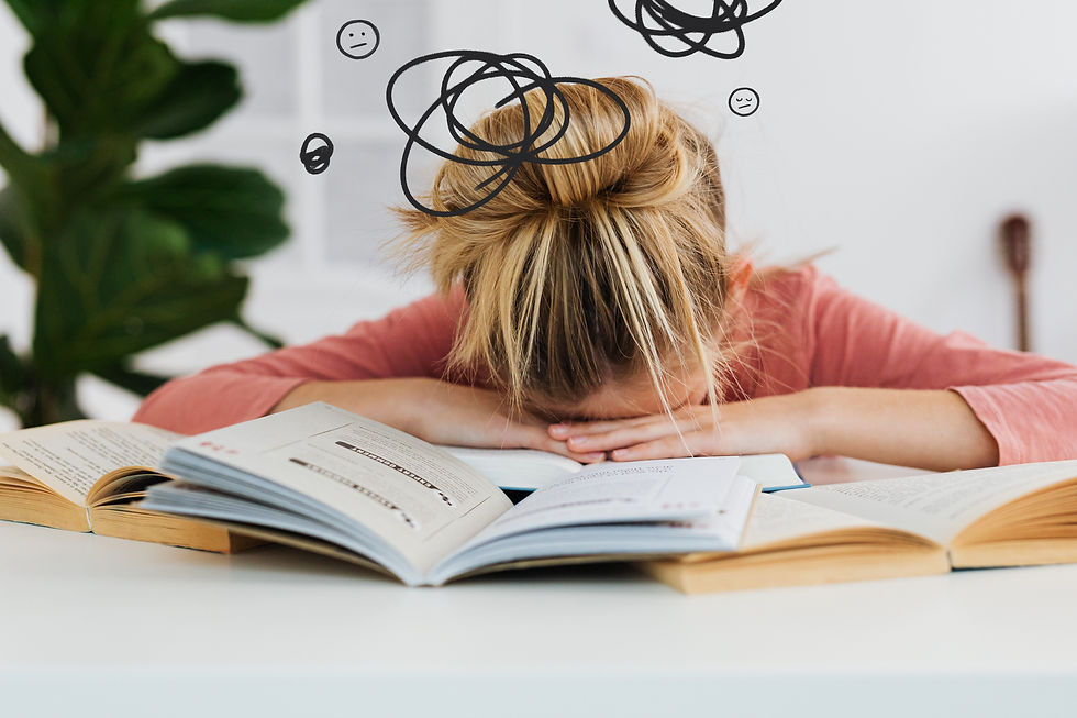Child surrounded by school books with her head in her hands