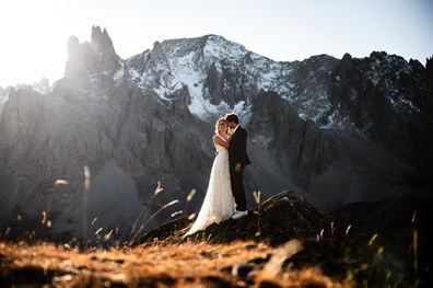Photo de mariage prise par Thomas Beauquesne au sommet d'une montagne dans les Alpes, montrant deux mariés au coucher de soleil. Photographe de mariage en Haute-Savoie. séance couple montagne.