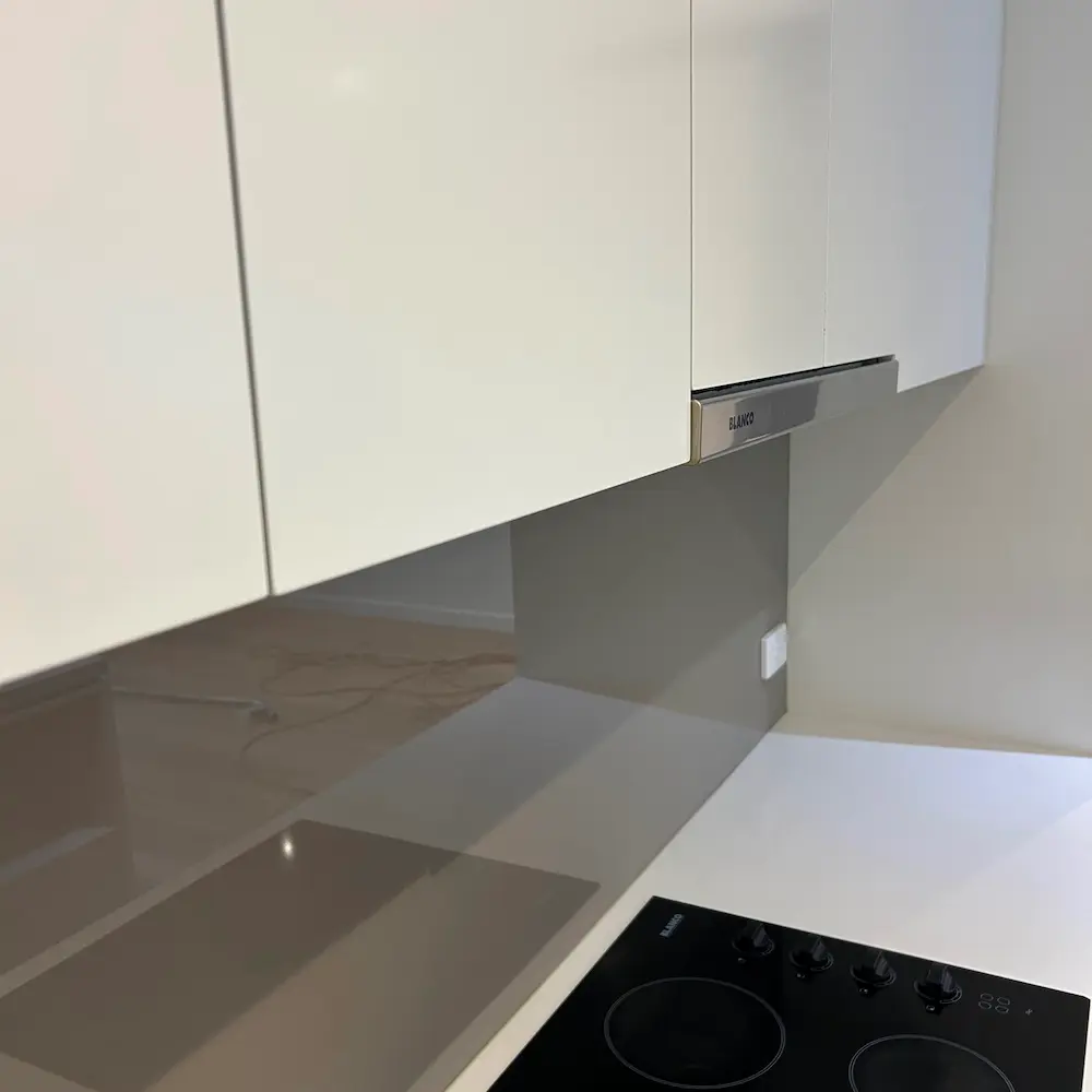 High-spec kitchen splashback, electric cooktop, and Blanco rangehood canopy detailed during 2 bed 1 bath spring cleaning