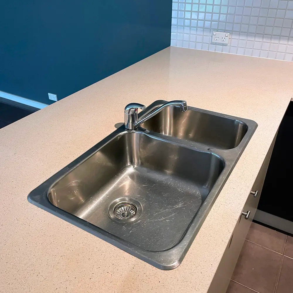 Engineered stone kitchen island benchtop and dual-bowl stainless steel sink descaled and polished by Whole Detail. 