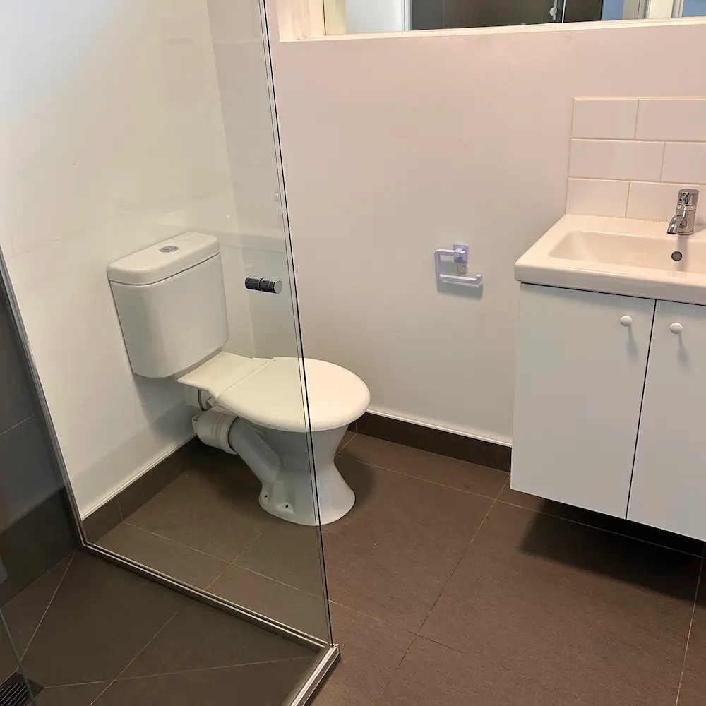 Second bathroom suite featuring descaled glass shower screen, sanitised toilet, and tile floor deep clean by Whole Detail. 