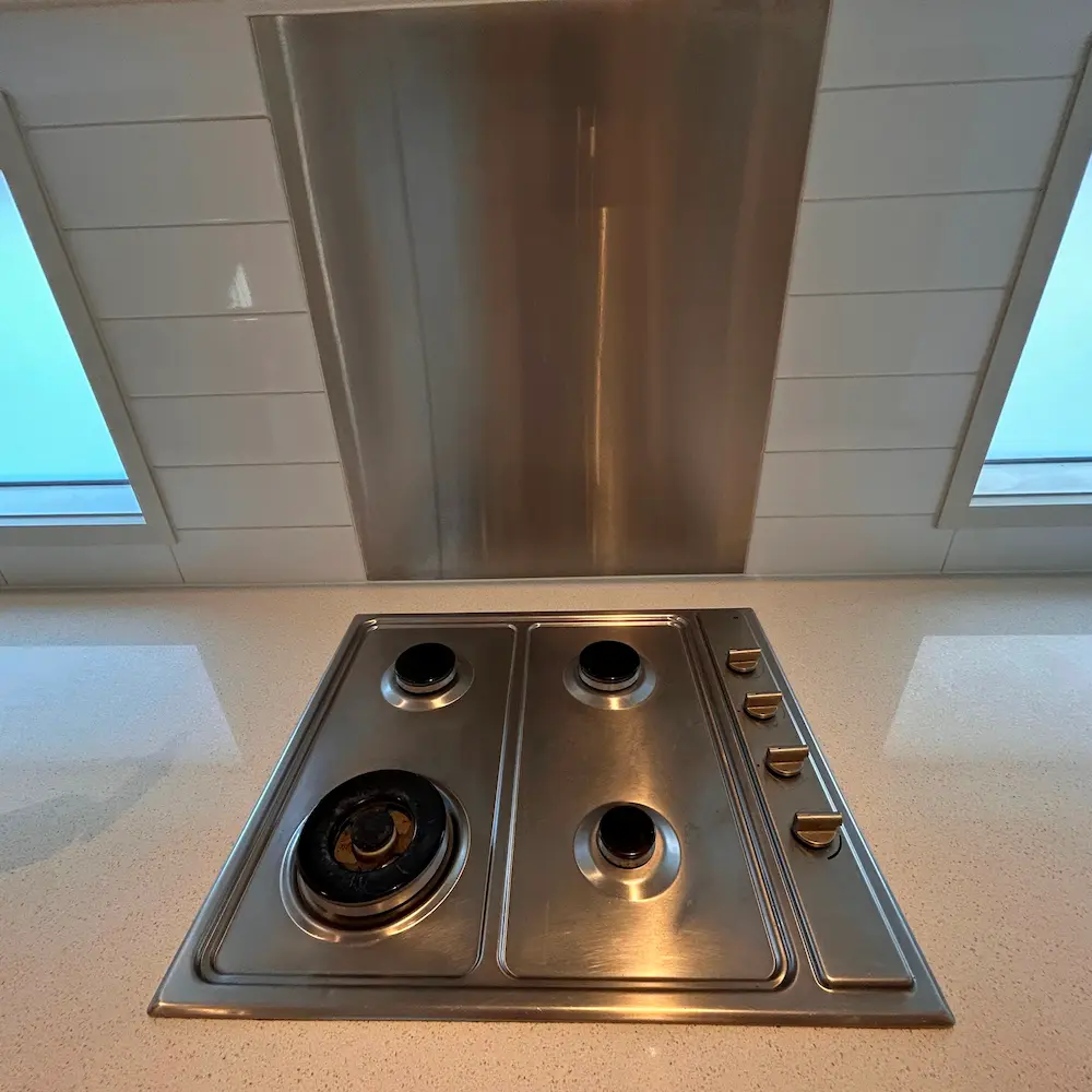 Stainless steel gas cooktop and tiled kitchen splashback degreased and detailed by Whole Detail. 