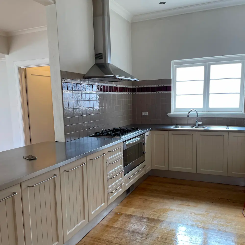 Spacious family kitchen with stainless steel rangehood canopy, gas cooktop, and polished timber floors detailed by Whole Detail. 