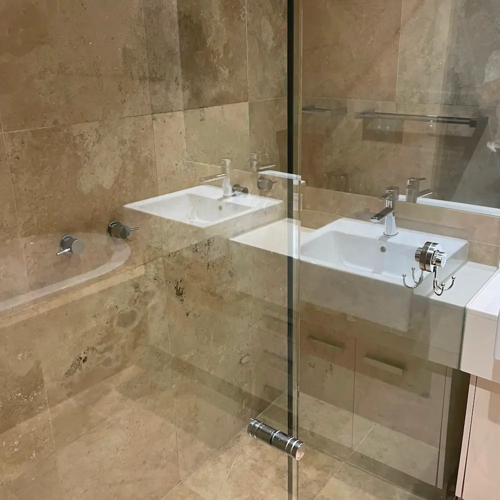 Travertine wall tiles, vanity basin, and glass shower enclosure descaled and polished during 5 bed 2 bath spring clean. 
