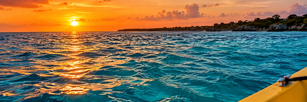Sunset over turquoise Caribbean waters with a coastline in the distance