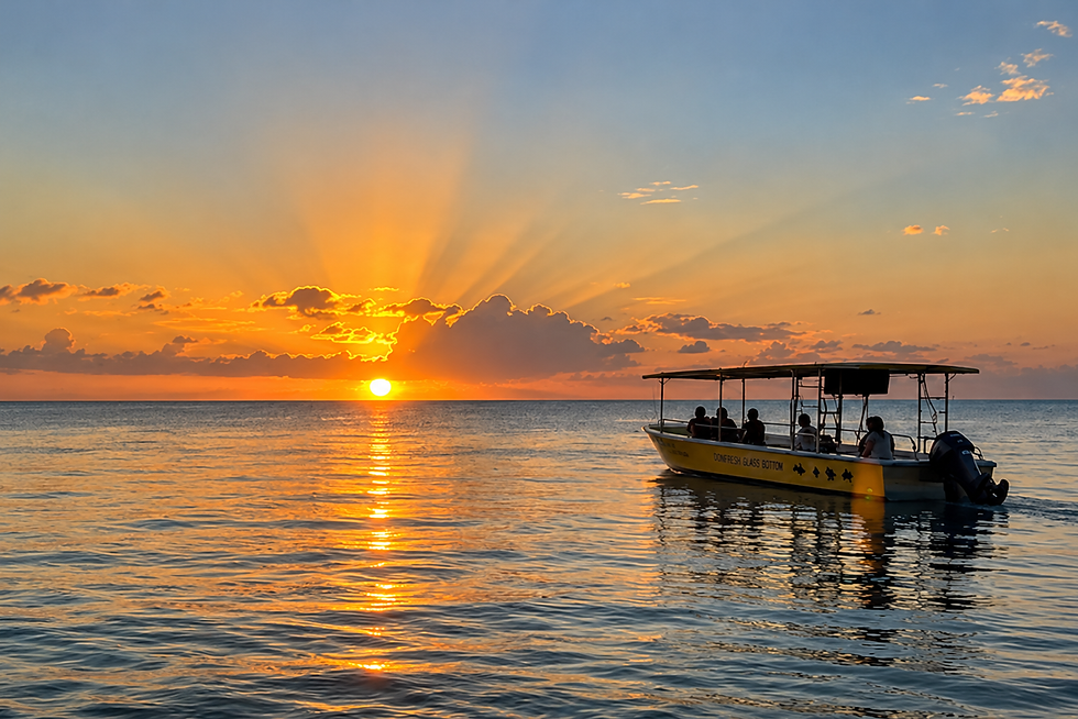 Boat cruising across the Caribbean Sea during a golden sunset in Negril