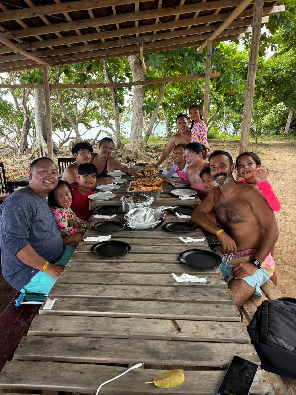Group of guests enjoying a meal together under an open-air shelter on Booby Cay