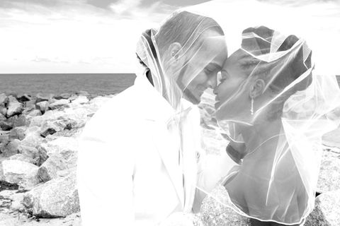 Black and white photo of newlyweds under bride's veil in Dania Beach, FL