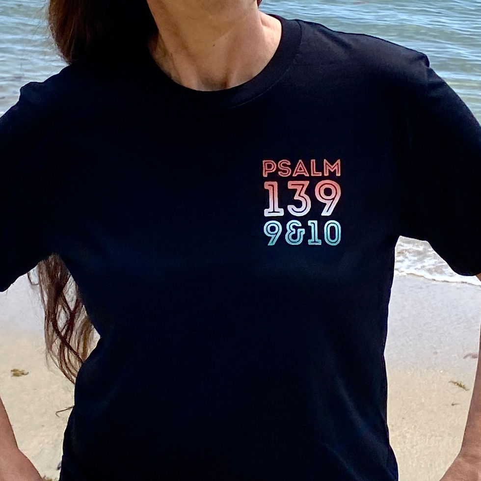 Close-up of black t-shirt displaying PSALM 139 9&10 text near ocean.