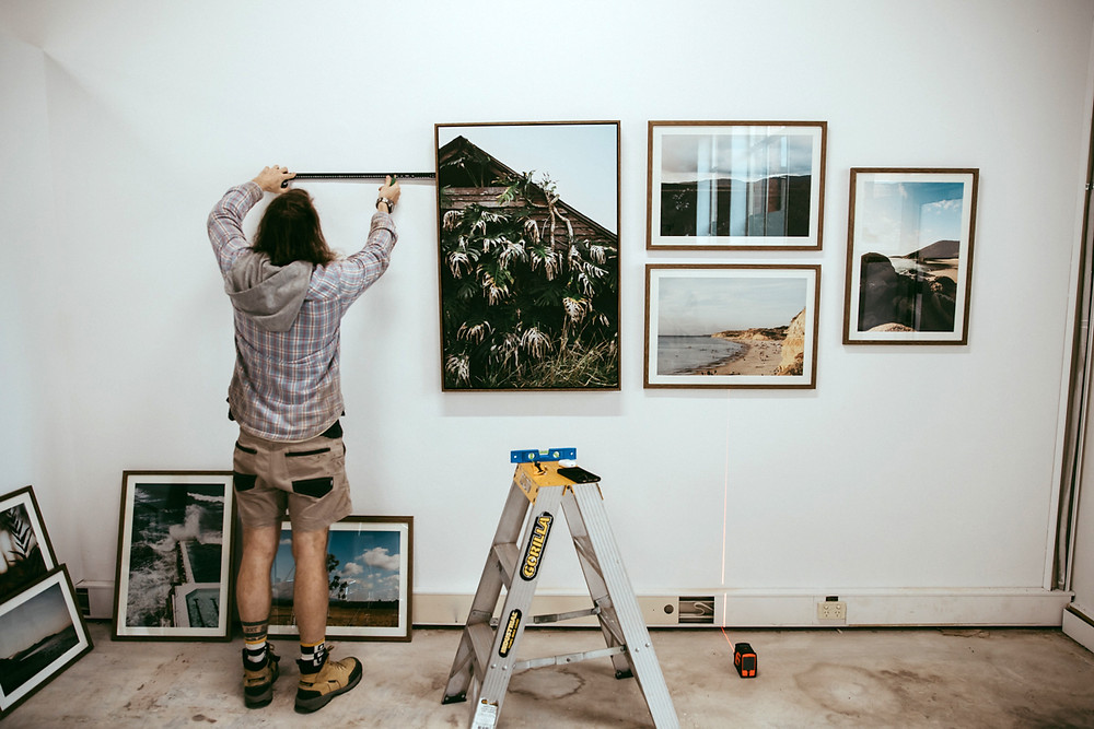 Scott hanging the photographs, tape measure in hand, getting the levels just right!