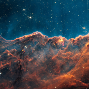 A nebula resembling a hazy orange cloud below a thinner blue one. Stars are scattered across.