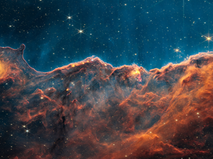 A nebula resembling a hazy orange cloud below a thinner blue one. Stars are scattered across.