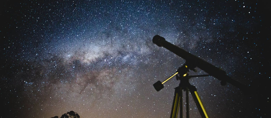 A small telescope with a thin tube before a Milky Way backdrop.