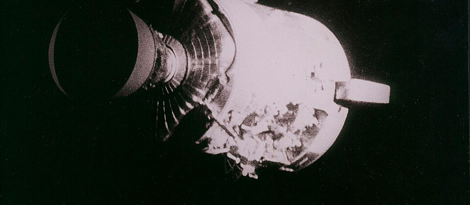 The Apollo 13 service module in black and white. The top half is smooth and covered, but the bottom half has exposed interior.
