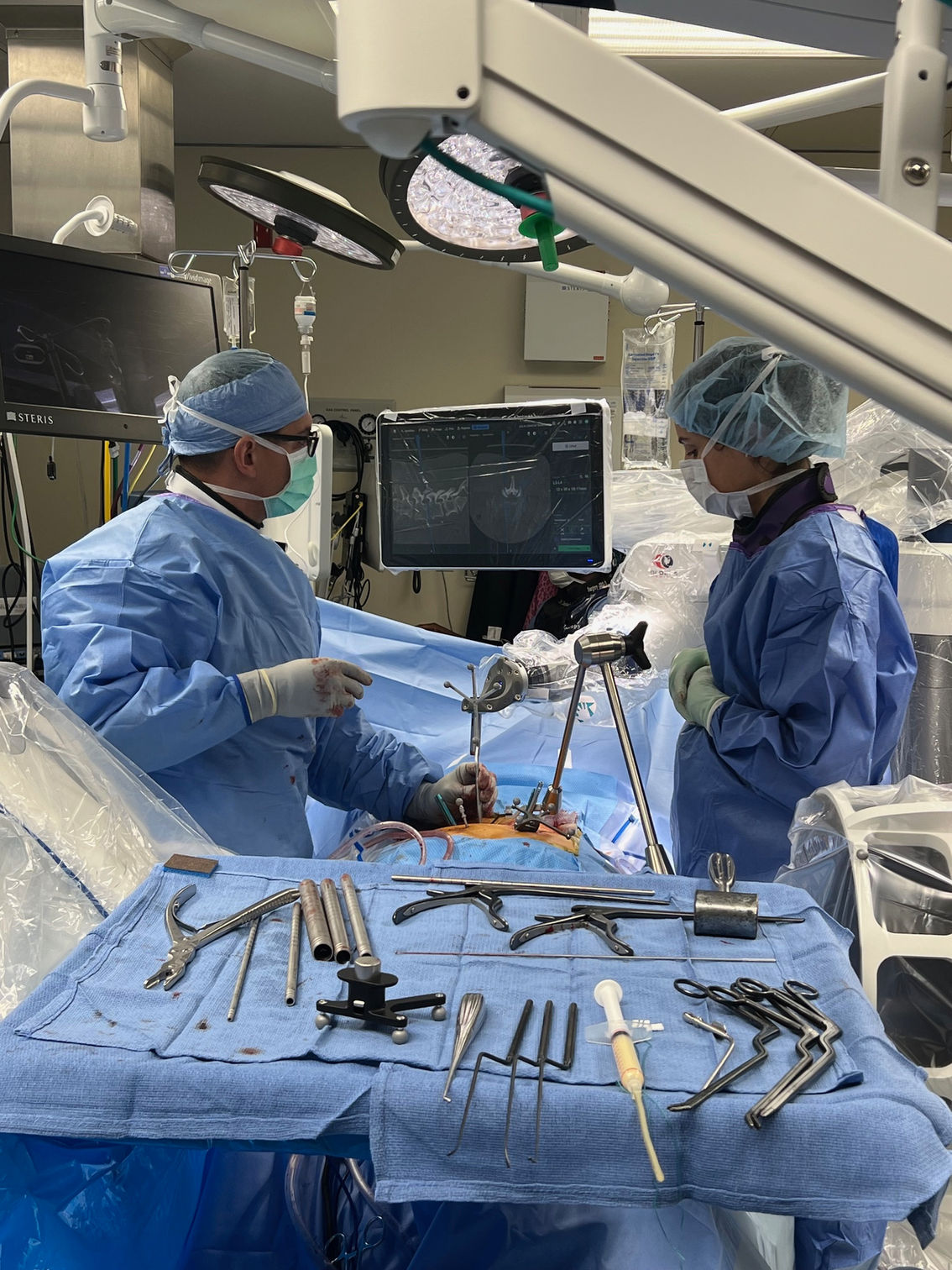 Surgeons performing a surgical procedure, medical equipment on surgical table, in operating room.