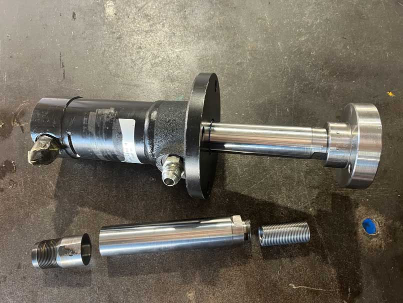 Re-engineered hydraulic cylinder ram and punch press component ready for reassembly.