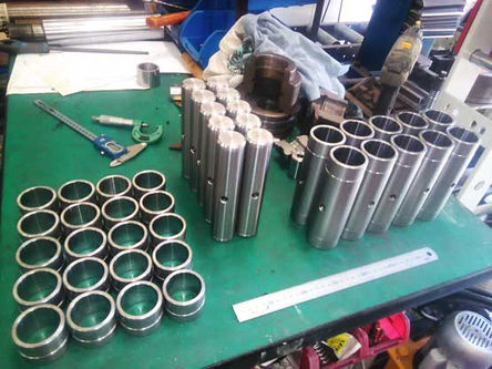 Various Pins , Bushes and Sleeves that were CNC machined, on a workbench.