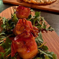 Pizza on a serving board next to shrimp on a serving board