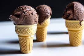 3 chocolate ice creams in cones on a table