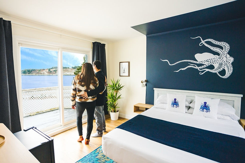a couple standing bythe window in their room at the marmalade motel overlooking the ocean