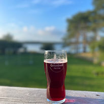Craft beer on a wood railing overlooking the ocean