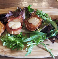 Up close of bacon wrapped scallops on a serving board