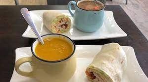 two plates of soups and wraps in beautiful metal mugs