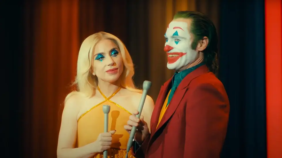 Joker y Harleen sosteniendo un micrófono en un escenario