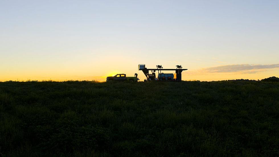 Top Deck Ag equipment in silhouette at sunset in a field.