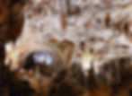 Illuminated cave interior with majestic stalactites and stalagmites. Soft yellow and blue lighting creates a serene, awe-inspiring atmosphere.