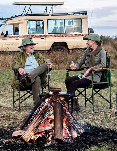 Man and woman on African safari sitting by a campfire talking
