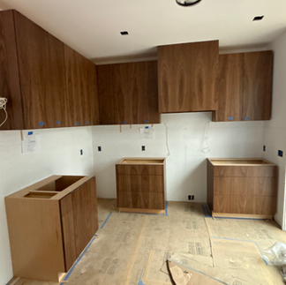 A kitchen under construction featuring custom cabinetry and countertops being installed.