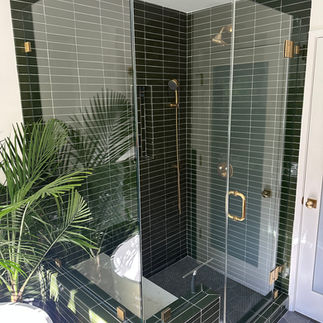 Stylish bathroom with green tile and a glass shower, representing luxury bathroom remodels in the Bay Area.