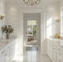 Elegant white bathroom featuring marble countertops and a chandelier, showcasing high-end home renovations.