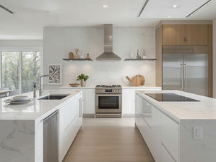 A high-end remodeled kitchen featuring sleek white marble countertops and modern appliances.