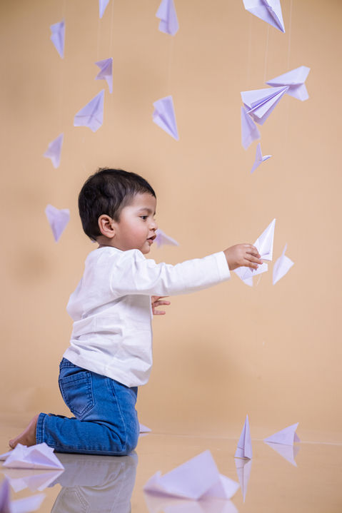 Indoor baby photo studio candid laughing moment during paper plane theme pre-birthday shoot by LensAction Photography Vizag