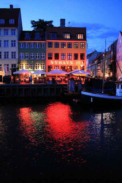 ライトアップされた水辺の飲食店街が水面に映り、空は青暗いコペンハーゲンの街並み