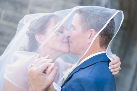 a bride and groom kiss under a veil
