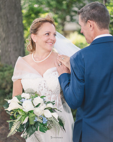 the bride is wearing a pearl necklace and the groom is wearing a blue suit