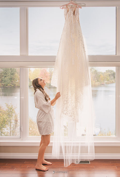 a bride in a white robe is looking up at her wedding dress