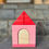 Thumbnail: Pink wooden house with red roof, wooden door, and steps in background.