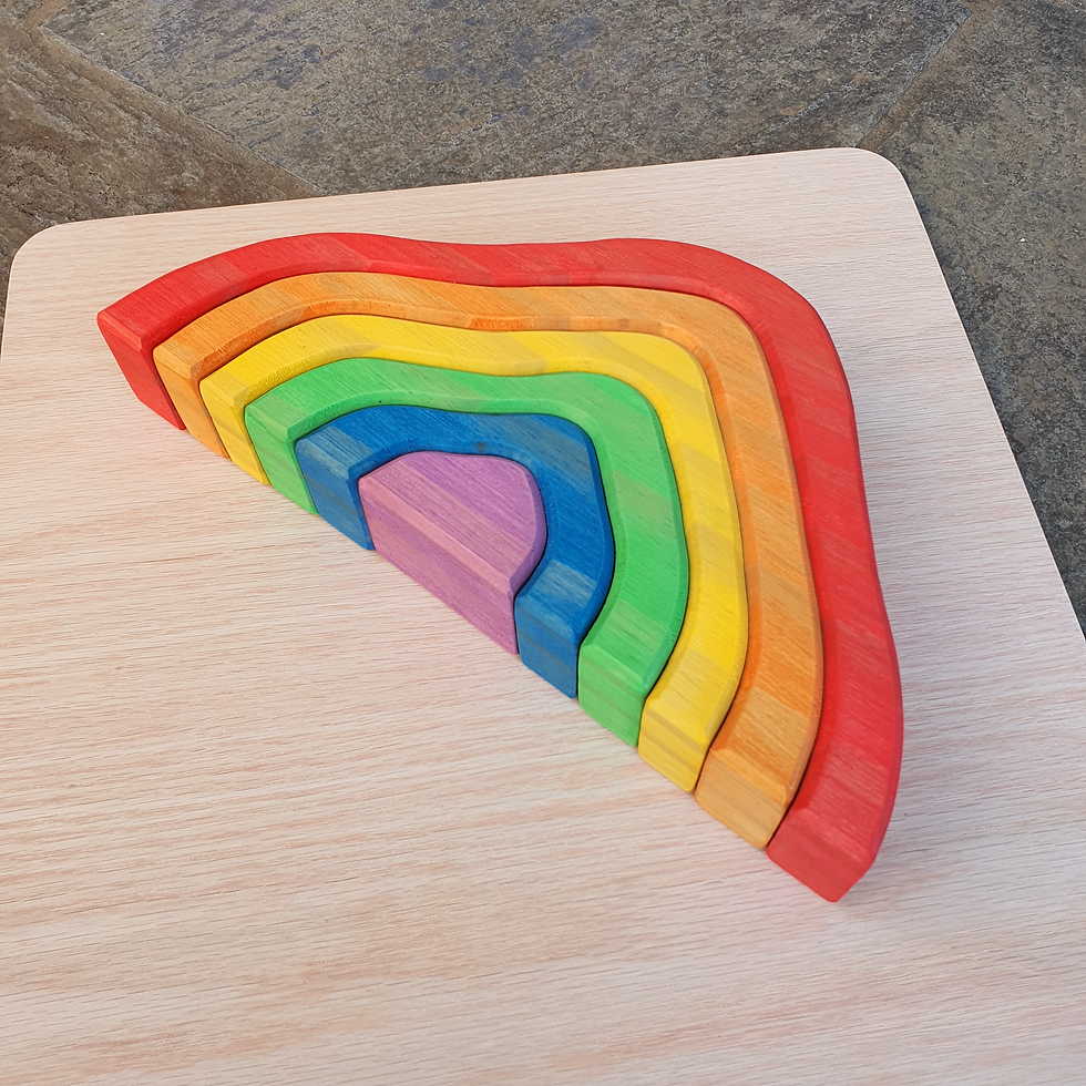 Thumbnail: Colorful wooden rainbow toy; Serenitoys Triangles - Frosted; stacked on a wooden board