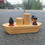 Thumbnail: Wooden toy boat with passengers and a black cone, outdoors.