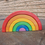 Thumbnail: Wooden rainbow toy with colorful arches, outdoors on a stone surface. Serenitoys.