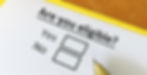 A close-up of a person filling out a paper form that asks, “Are you eligible?” representing the first step in the family petition process.
