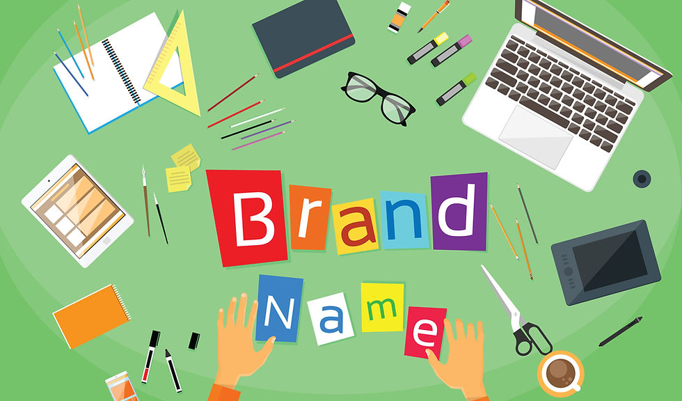 Hands arrange colorful letters spelling "Brand Name" on a green desk surrounded by art supplies, laptop, and tablet, evoking creativity.